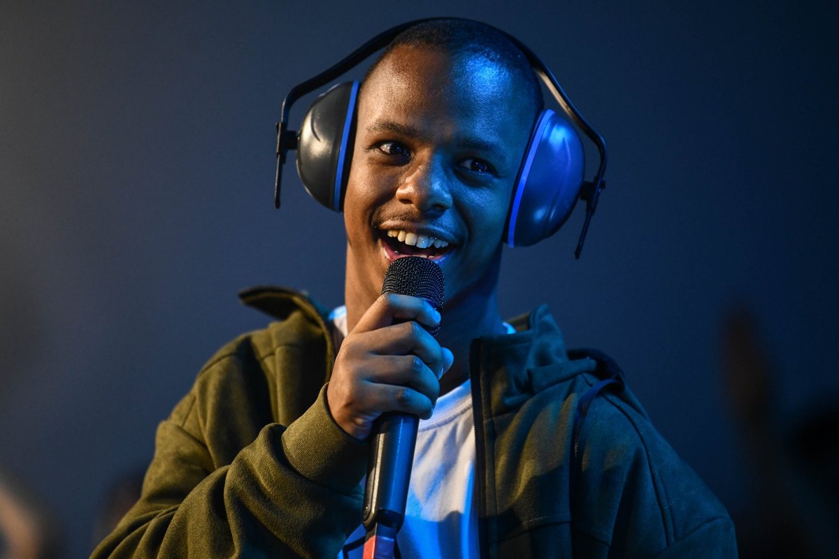 Jovem sorrindo com microfone e protetor auricular
